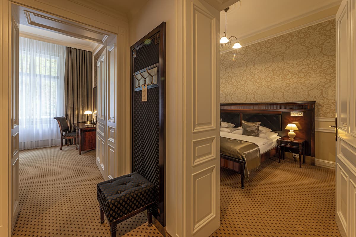 A hotel room with a large bed, bedside tables, a desk, and a chair.