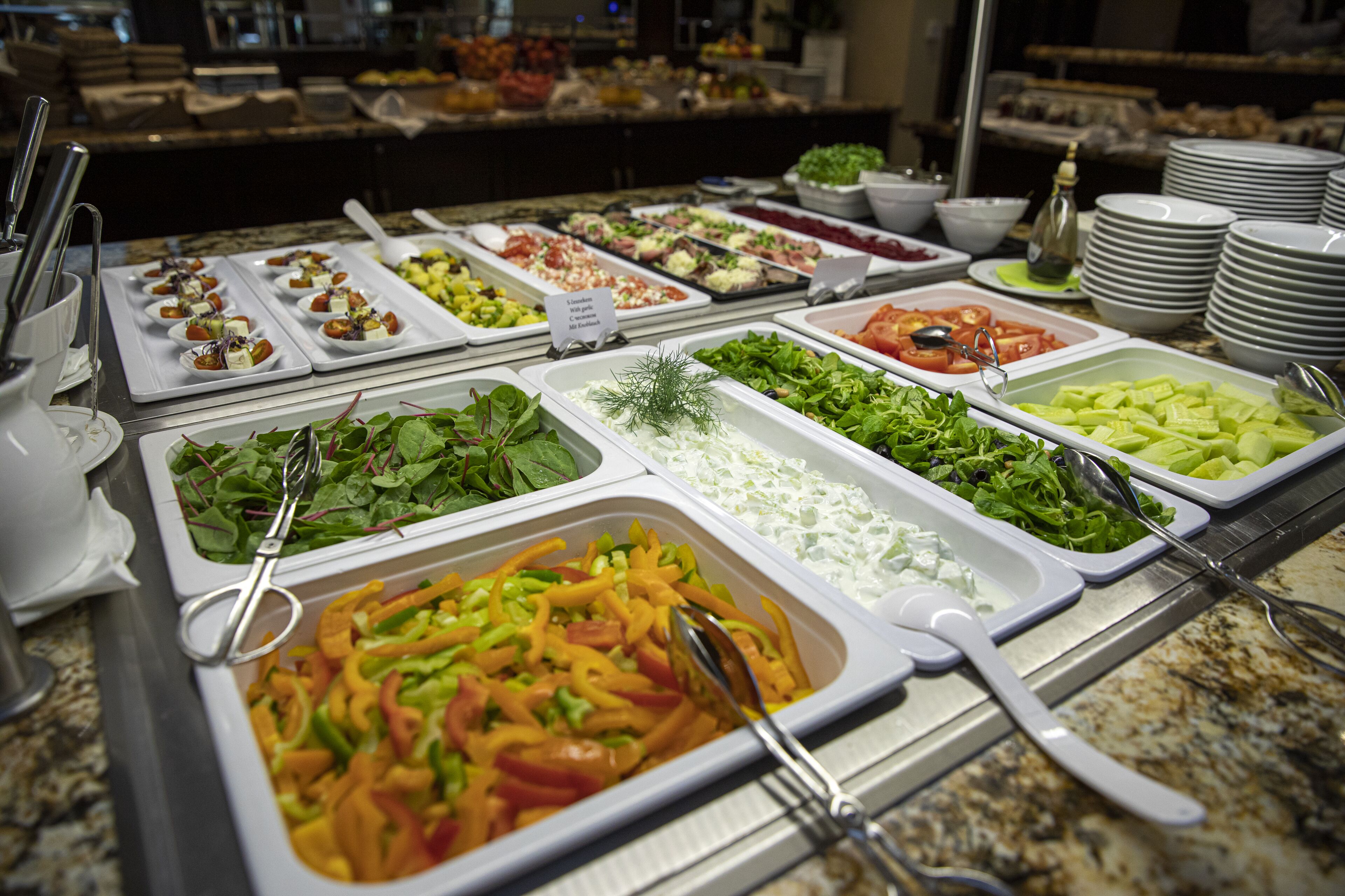 Un bufé con diversas opciones de comida, incluyendo ensaladas, verduras y carnes.