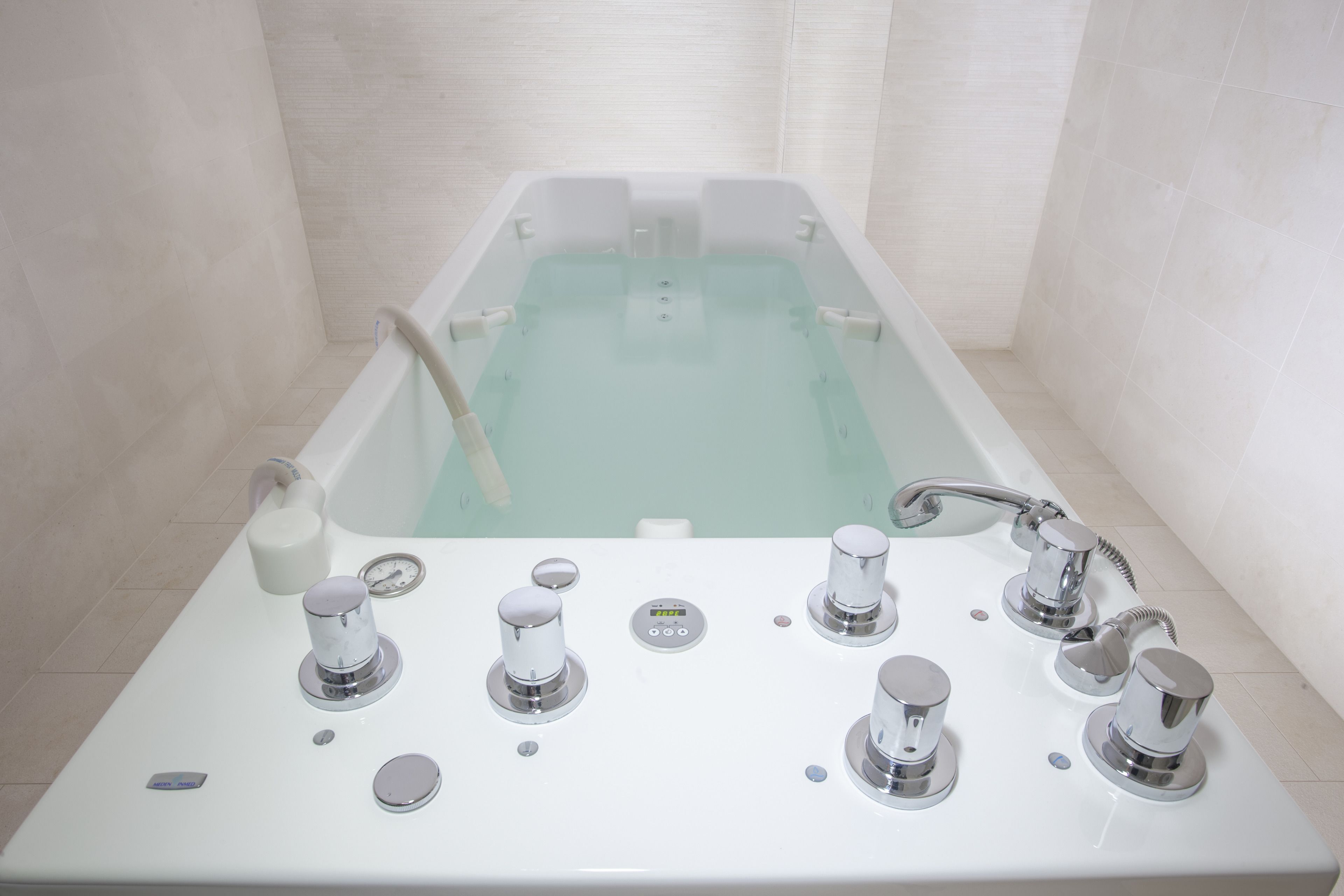 Ein modernes Badezimmer mit freistehender Badewanne, mehreren Wasserhähnen und einer Bedienkonsole.