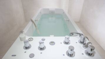 A modern bathroom with a freestanding bathtub, multiple faucets, and a control panel.