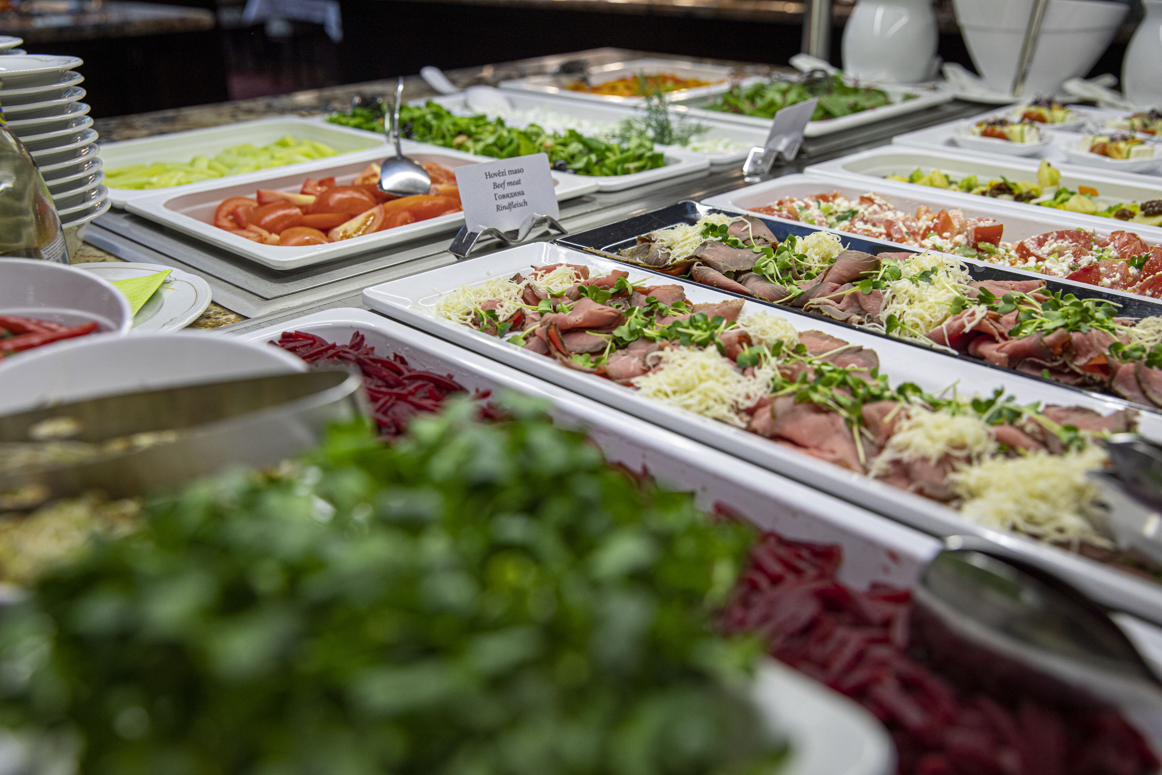 A buffet with various food options including meats, cheeses, and vegetables.