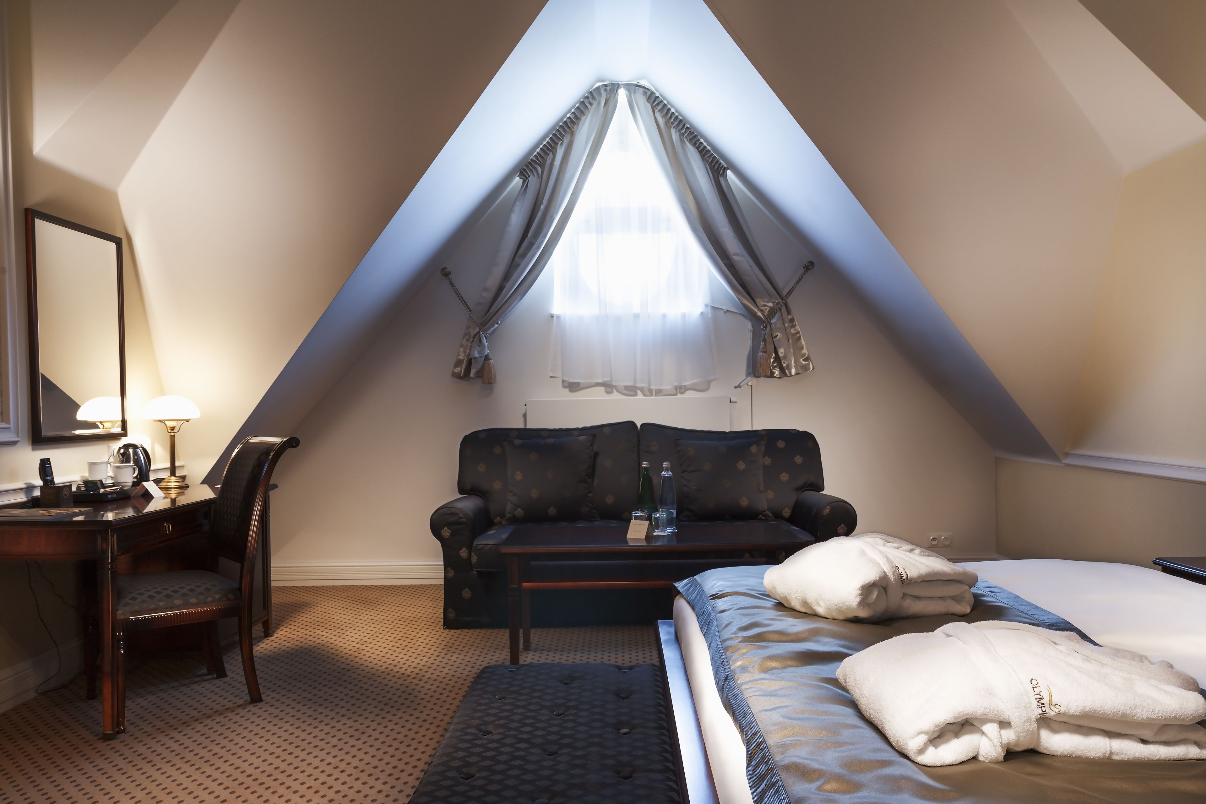 A cozy room with a bed, a desk, and a couch.