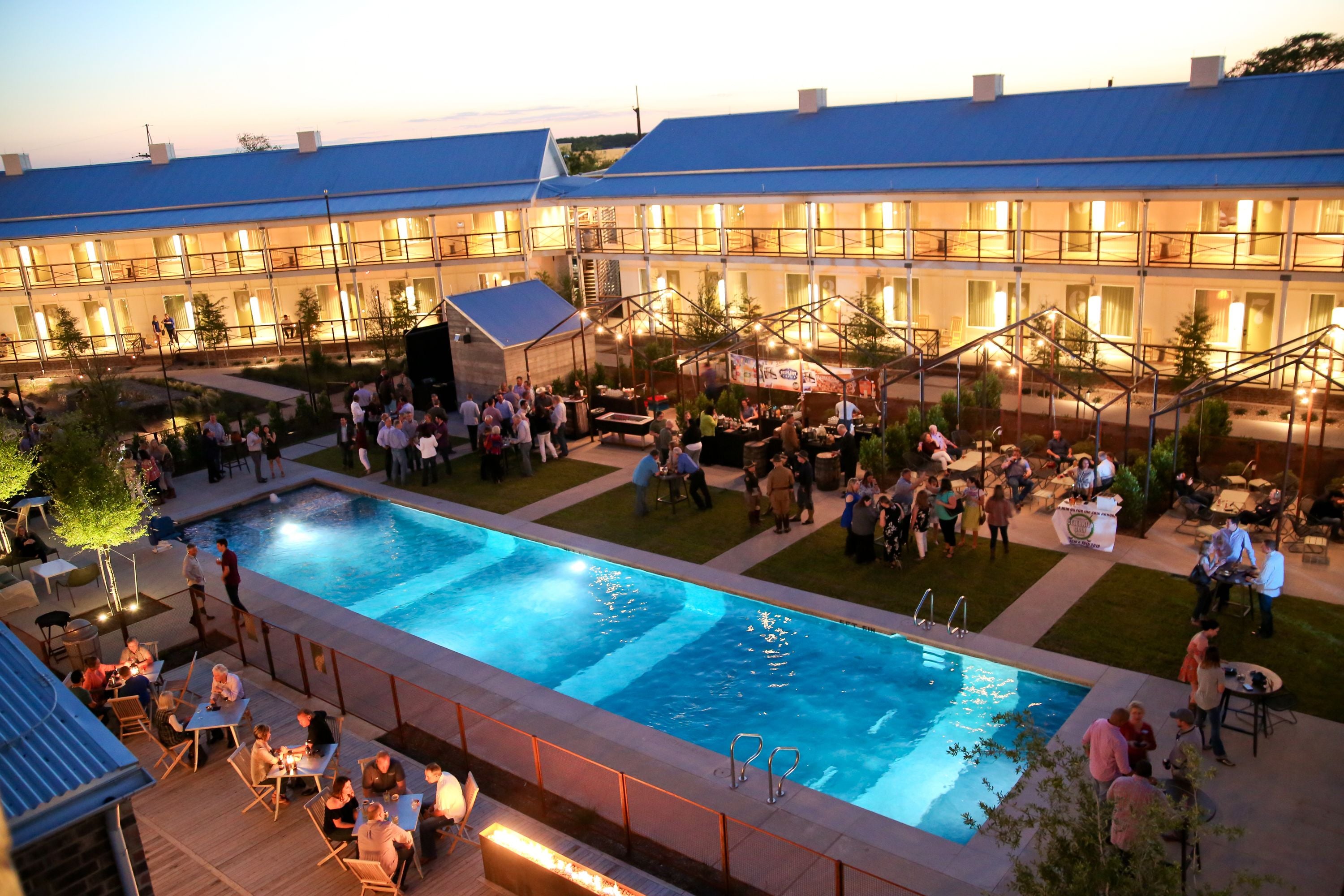 A poolside area with a swimming pool, outdoor seating, and a building with multiple balconies.