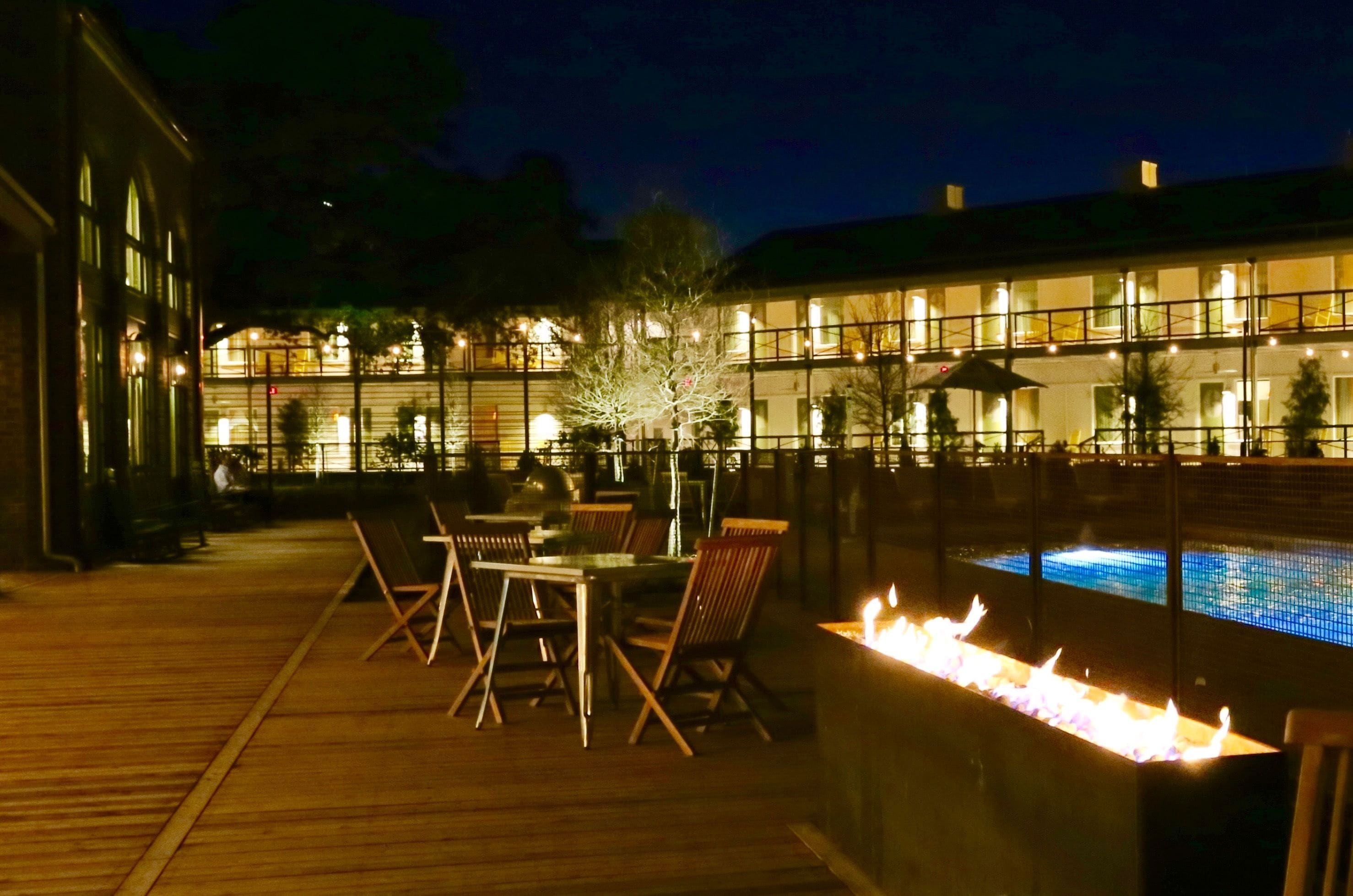 An outdoor dining area with a pool and fire feature.