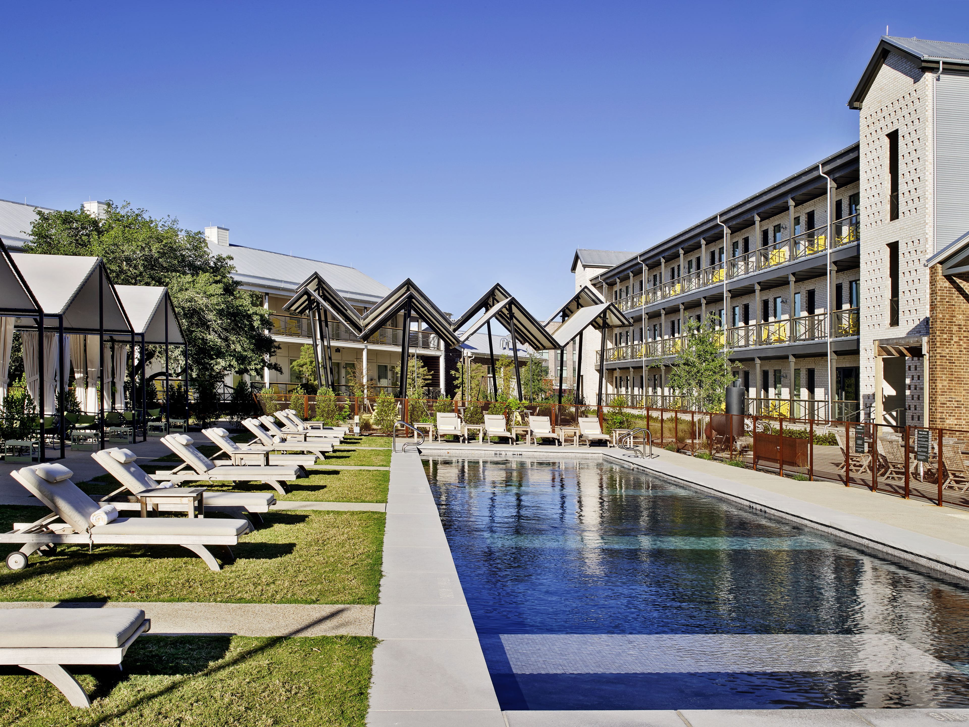 A poolside area with lounge chairs and a clear blue pool.