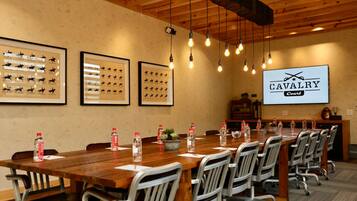 A conference room with a long wooden table, metal chairs, framed horse silhouettes on the wall, and a 'CAVALRY Court' sign.