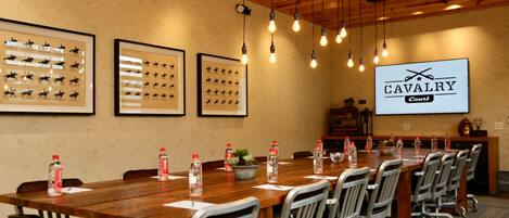 A conference room with a long wooden table, metal chairs, framed horse silhouettes on the wall, and a 'CAVALRY Court' sign.