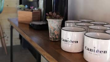 Una cafetera, una maceta y varias tazas sobre una mesa de madera.