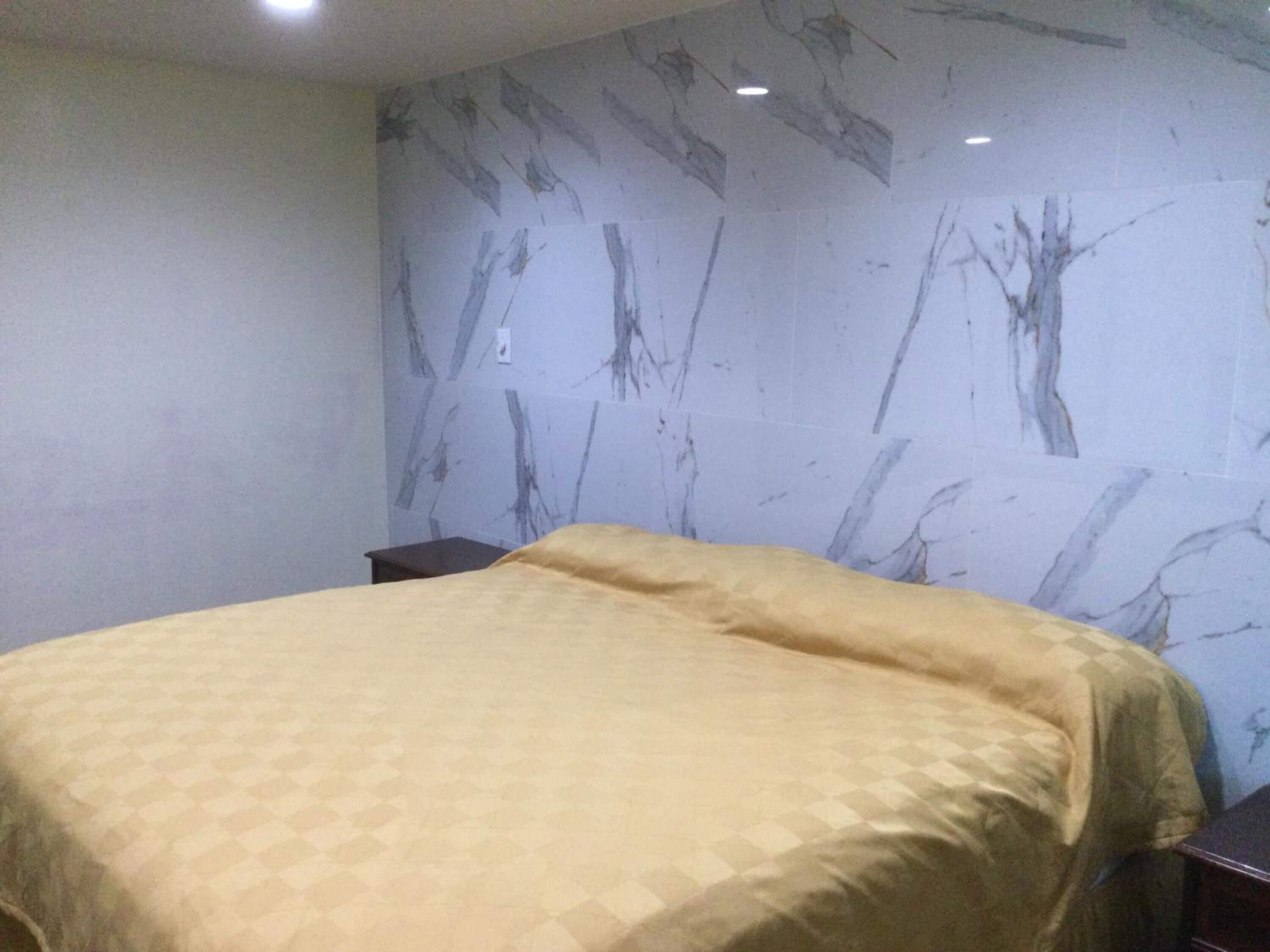 A room with a bed, a nightstand, and a wall with a marble-like pattern.