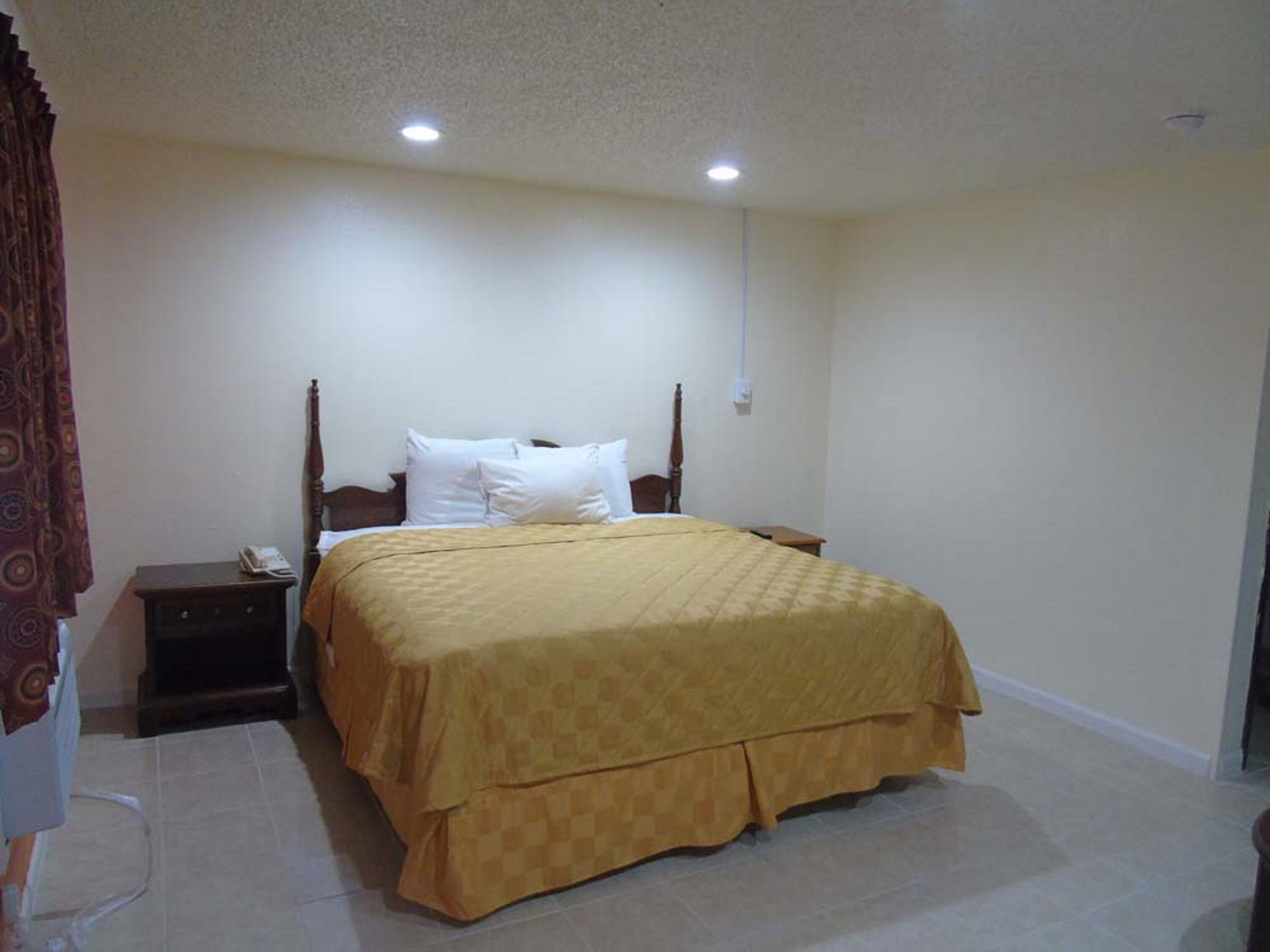 Un dormitorio con cama, mesitas de noche y una cortina.
