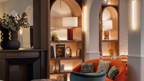 A cozy living area with a fireplace, a bookshelf, and a comfortable seating arrangement. - Hotel Grand Coeur Latin (Paris)