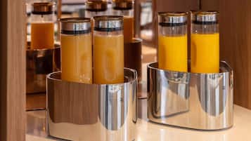 Un comptoir de petit-déjeuner doté de plusieurs distributeurs en acier inoxydable contenant du jus d’orange.