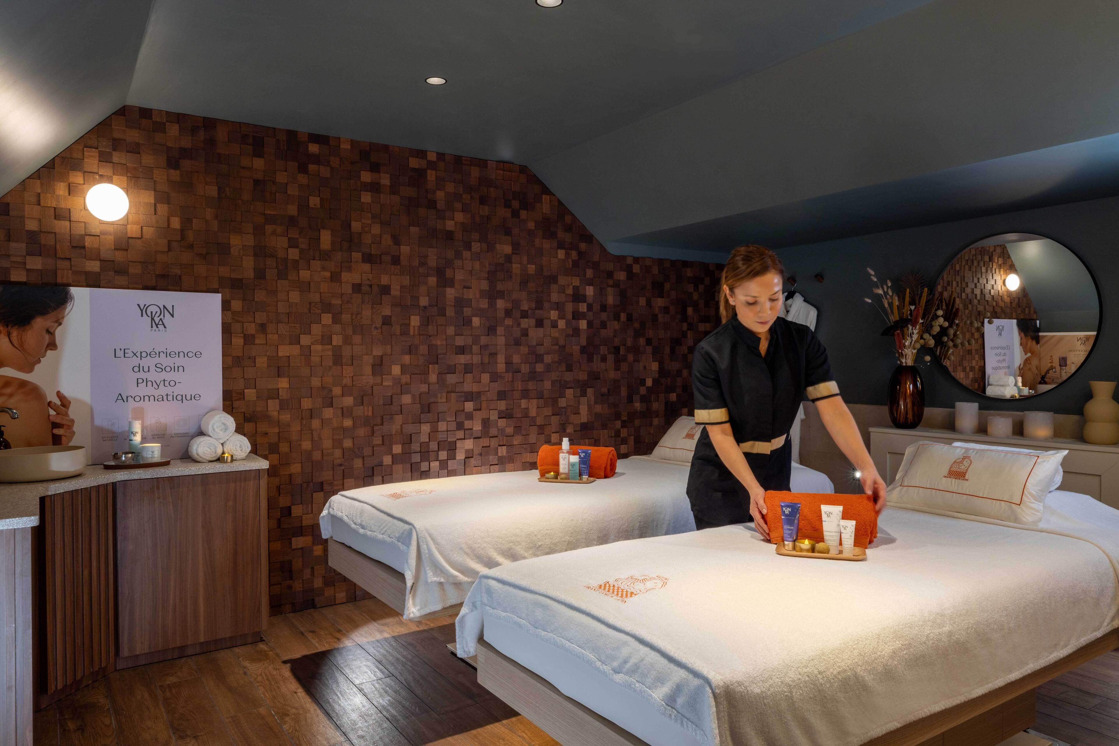 A spa room with two beds, a reception desk, and a wooden wall.