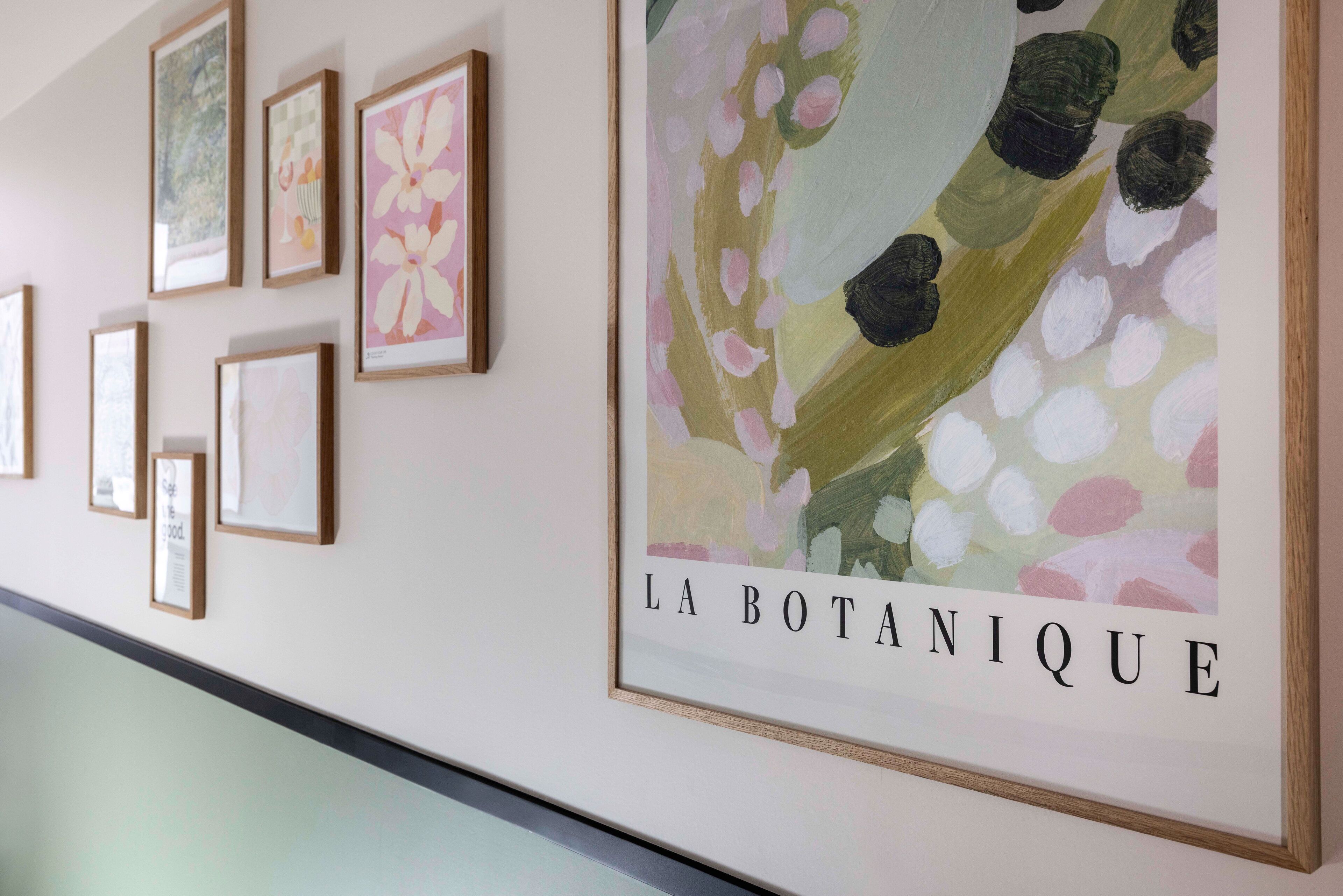 Un mur orné de tableaux botaniques encadrés, avec l’inscription « LA BOTANIQUE ».
