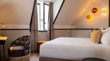 Una habitación de hotel moderna con una cama grande, una silla, una mesita y vistas al exterior.