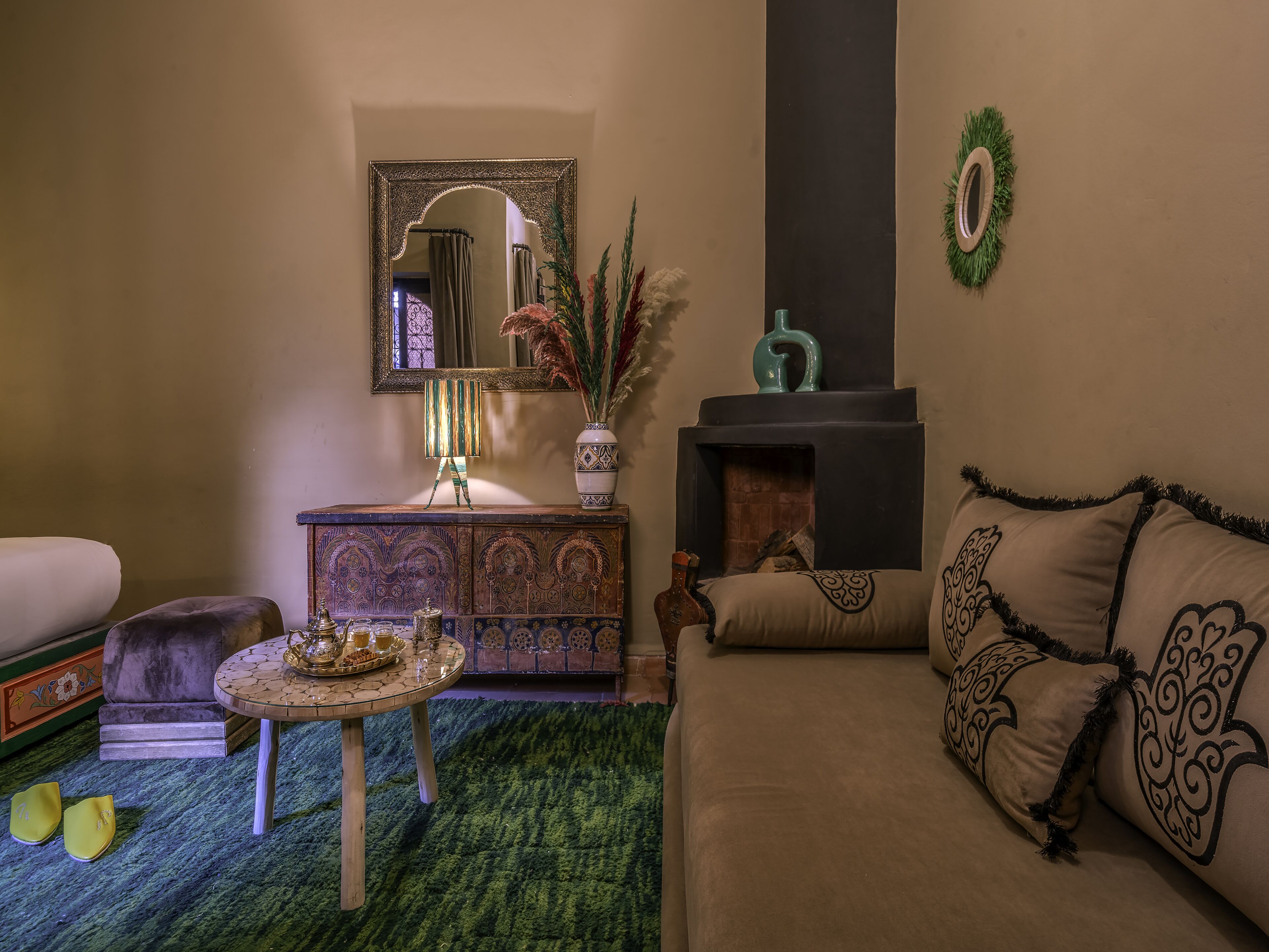 Una sala de estar acogedora con un sofá, una mesa de centro, una chimenea y un espejo decorativo.