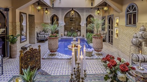 A luxurious indoor pool area with tiled flooring, ornate arches, and potted plants. - Riad Irhalne (Marrakech)