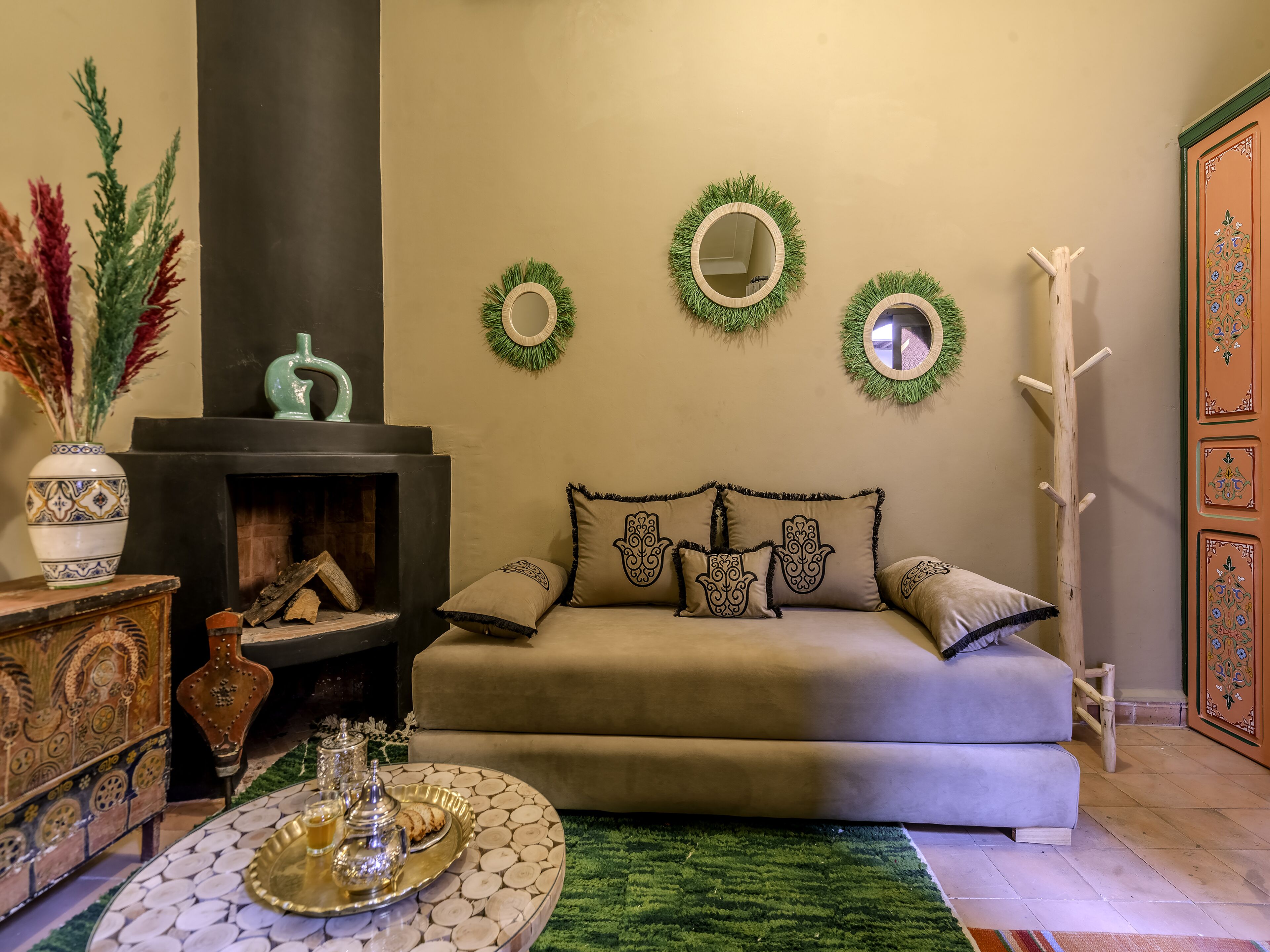 A cozy living room with a sofa, a fireplace, decorative wall mirrors, and a traditional wooden cabinet.