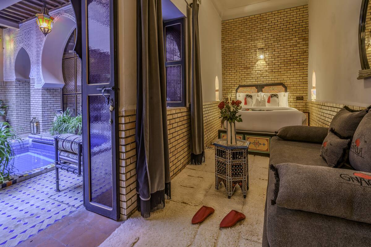 A cozy bedroom with a bed, a small table with a vase of flowers, and a sofa.