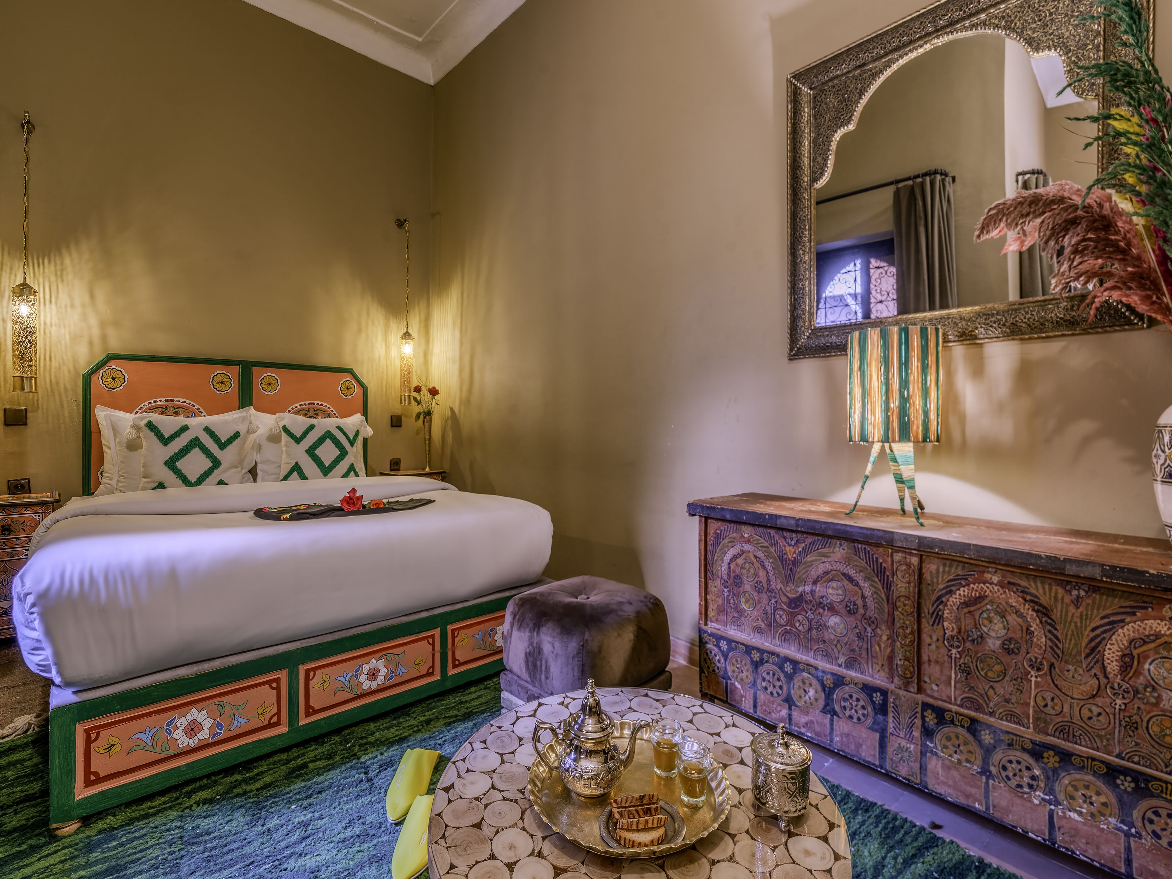 Une chambre à coucher bien rangée, avec un lit, une commode et un plateau décoratif contenant du thé et des en-cas.