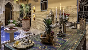 A traditional Moroccan interior with a tiled floor, a fountain, a table with a tray, and a hanging lantern. - Riad Irhalne (Marrakech)