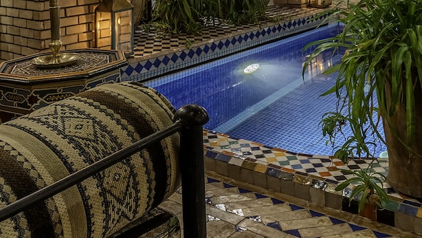 A pool area with a tiled floor, a brick wall, and a bench. - Riad Irhalne (Marrakech)