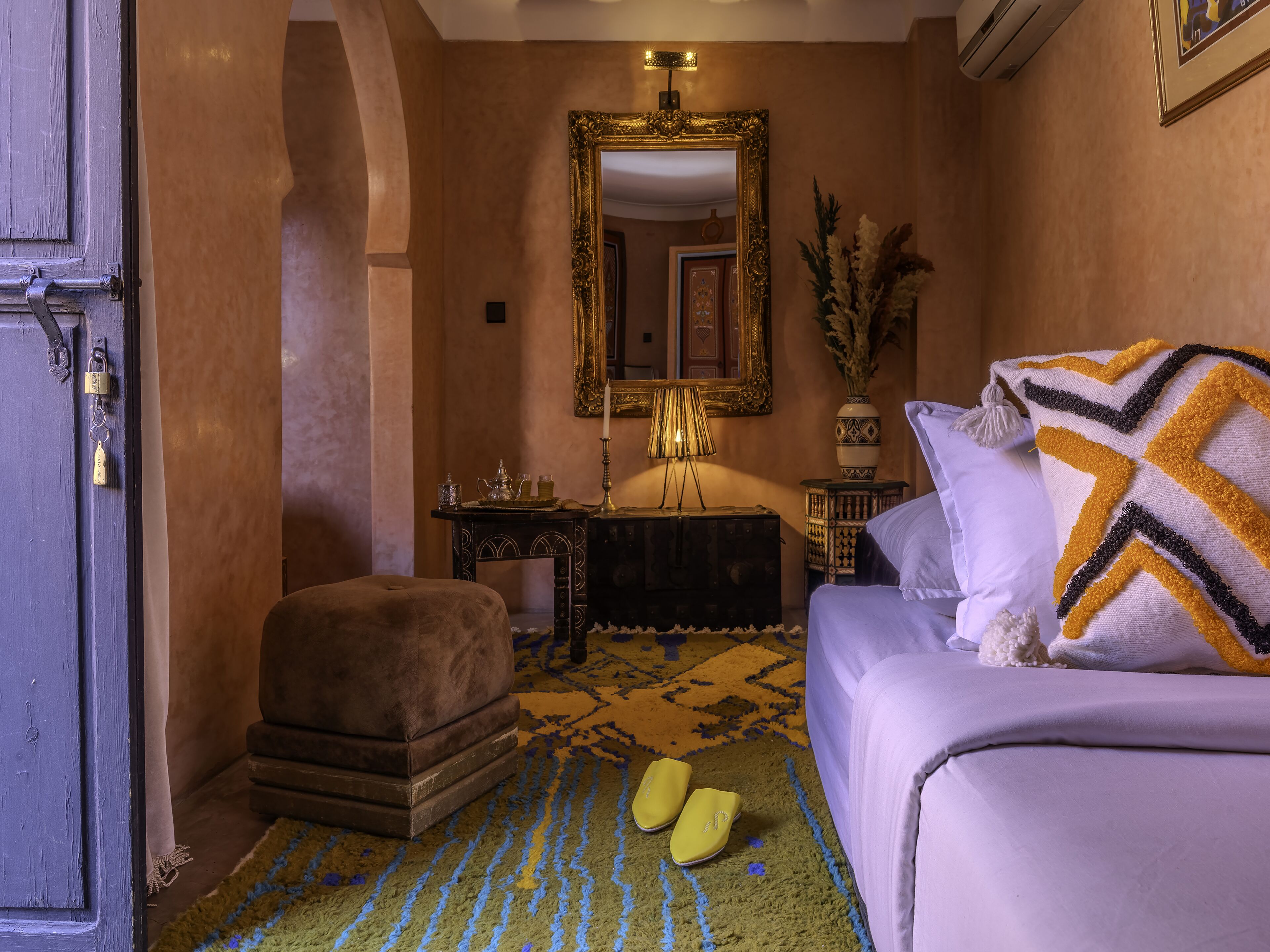 Une pièce comprenant un lit, une table de chevet, une commode, un miroir et une porte.