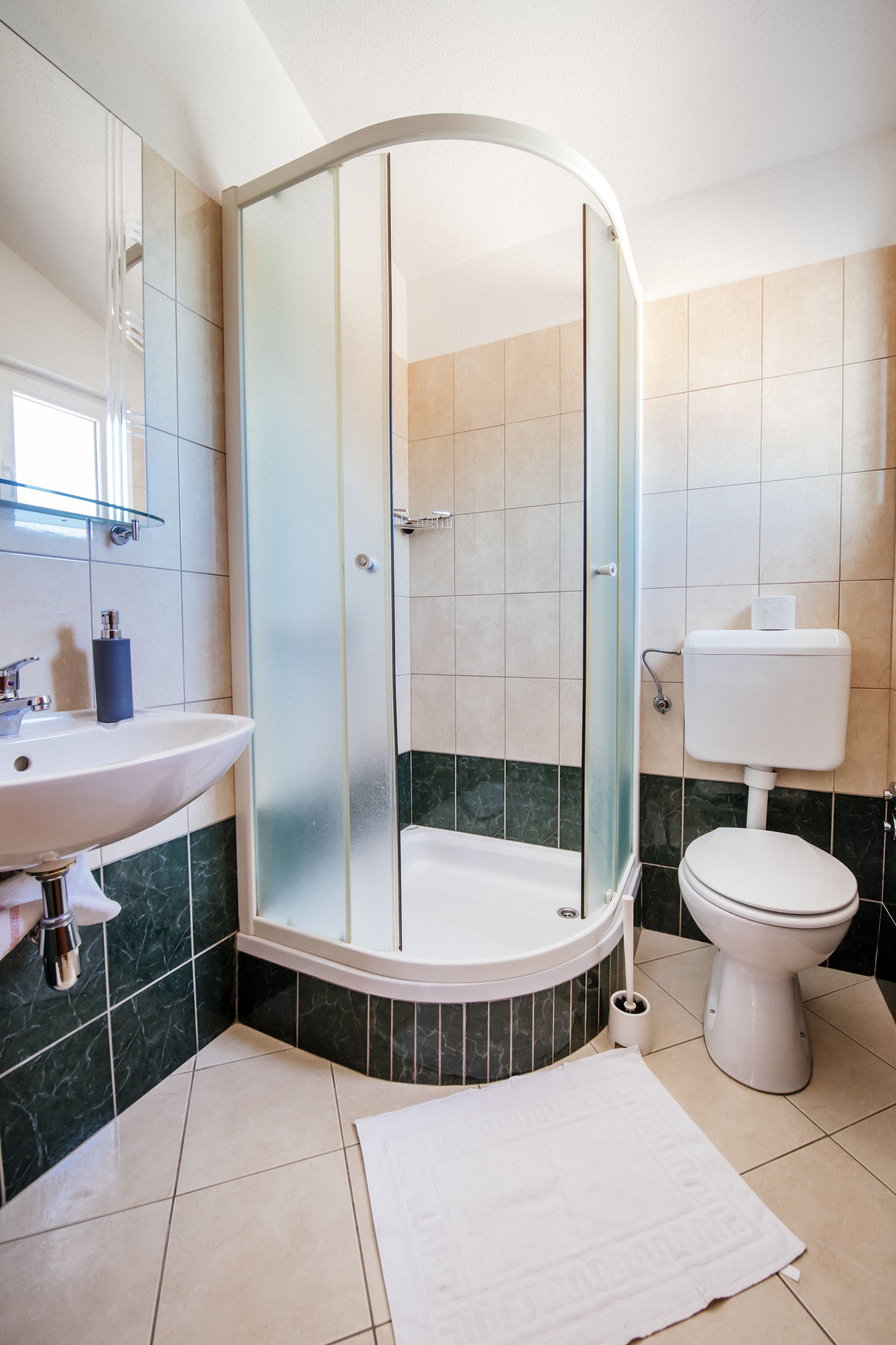 A modern bathroom with a curved shower enclosure, a white sink, and a toilet.