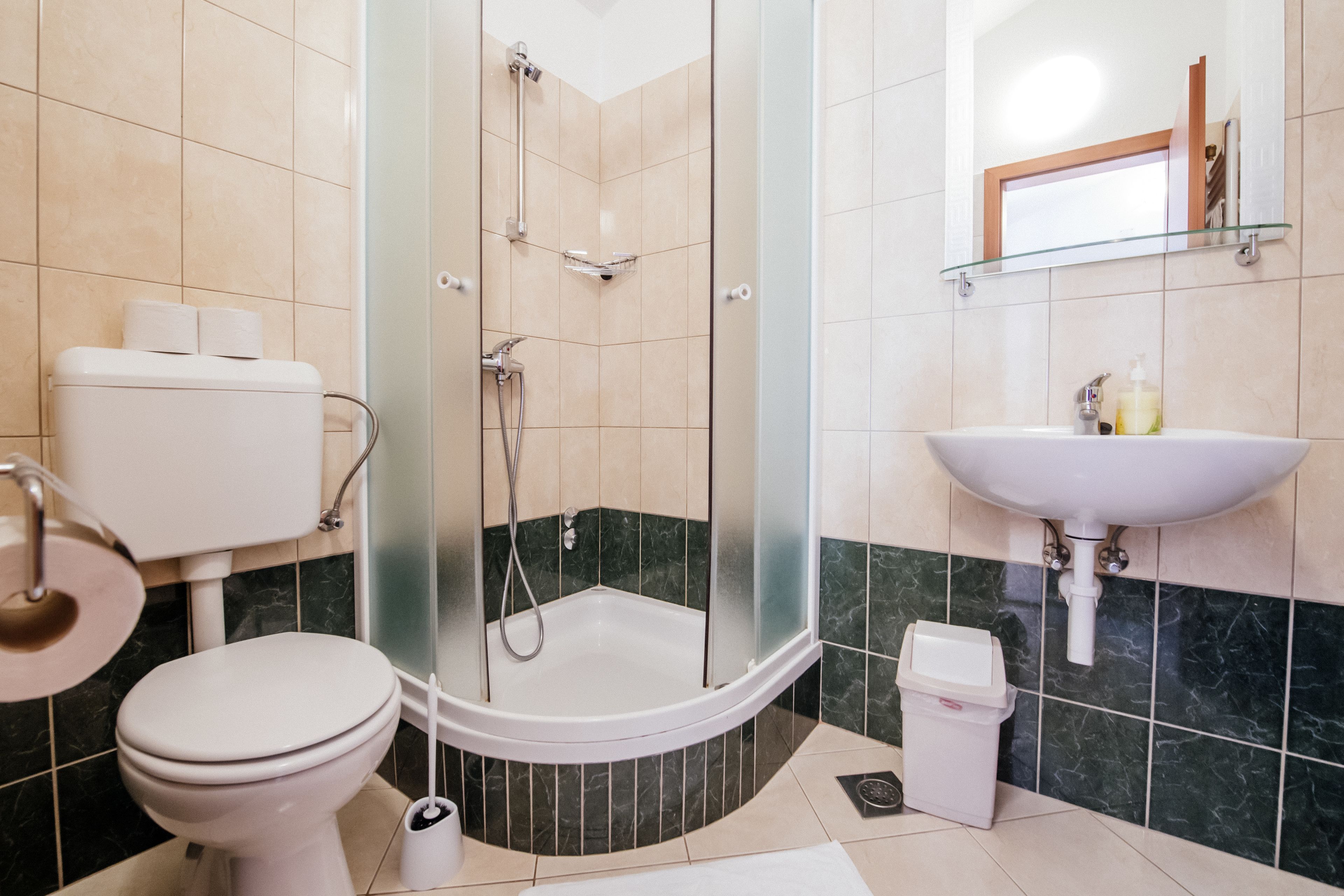 A bathroom with a toilet, shower, and sink.