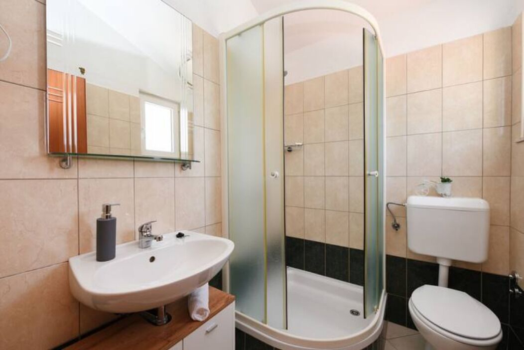 A modern bathroom with a glass-enclosed shower, a sink with a mirror, and a toilet.