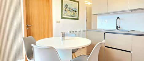 A modern kitchen with a round dining table, grey chairs, and wooden flooring.