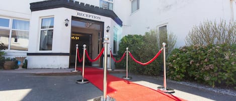 A reception area with a red carpet and metal stanchions.