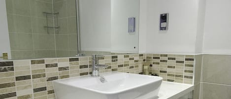 A modern bathroom with a large sink, a shower, and a toilet.