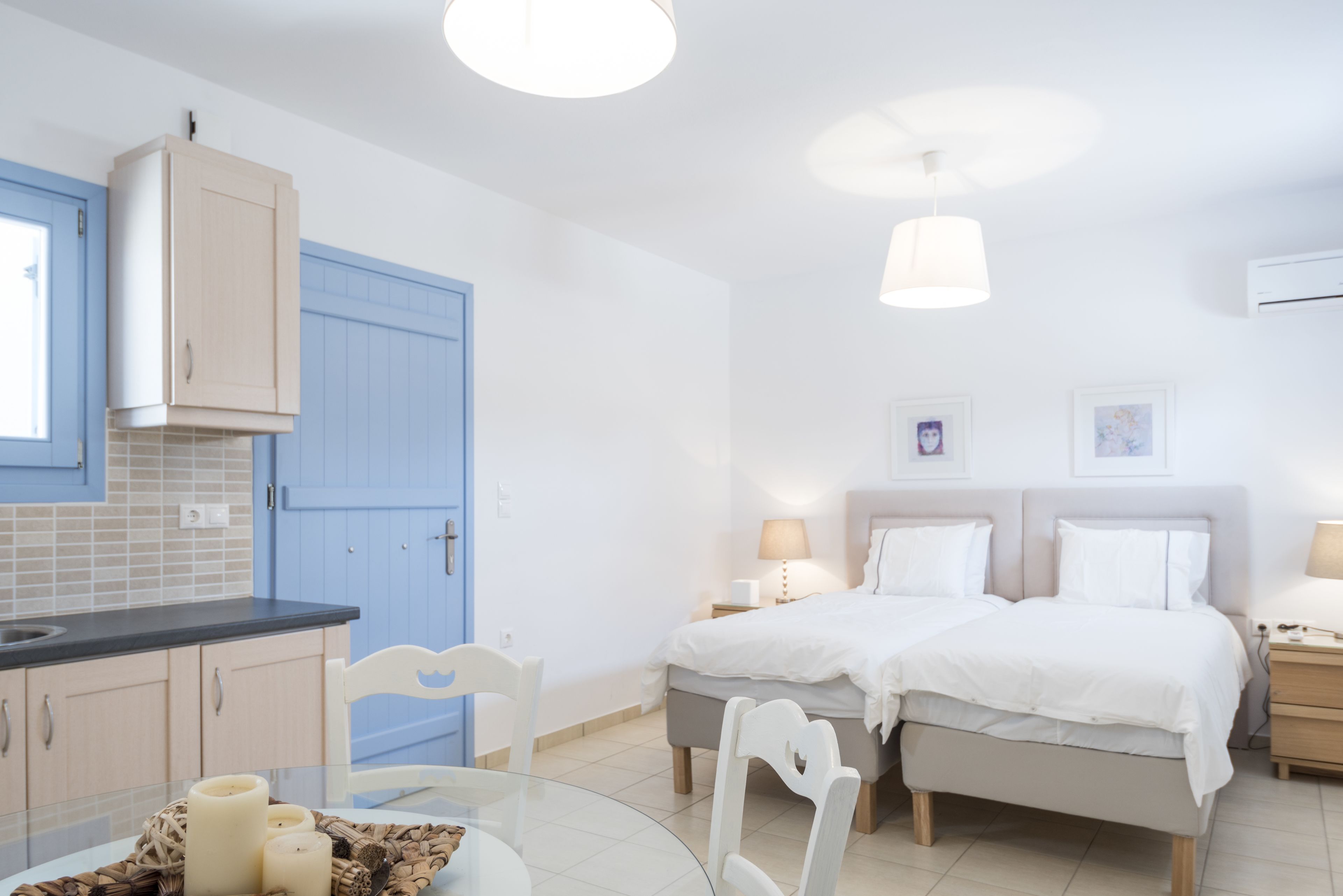 Een moderne hotelkamer met een keukenhoek, twee bedden, een eettafel en een zithoekje.