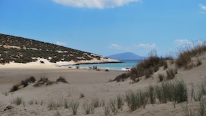 A beach with sand dunes, a clear sky, and a distant mountain. - Naxian Resort (Naxos)