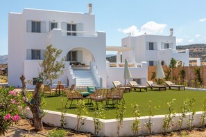 Una villa blanca con terraza en la azotea, mobiliario exterior y vistas al paisaje.