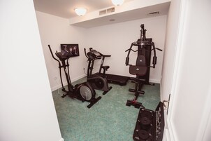Un gimnasio en casa con una bicicleta estática, una elíptica y un banco de pesas.