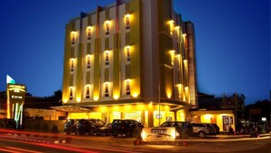 Un hôtel à plusieurs étages, doté d’une façade moderne, de fenêtres illuminées et d’une enseigne indiquant qu’il s’agit d’un hôtel.