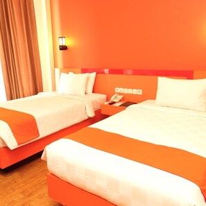 A hotel room with two beds, a nightstand with a phone, and a wall-mounted light. - Halogen Hotel (Sidoarjo)