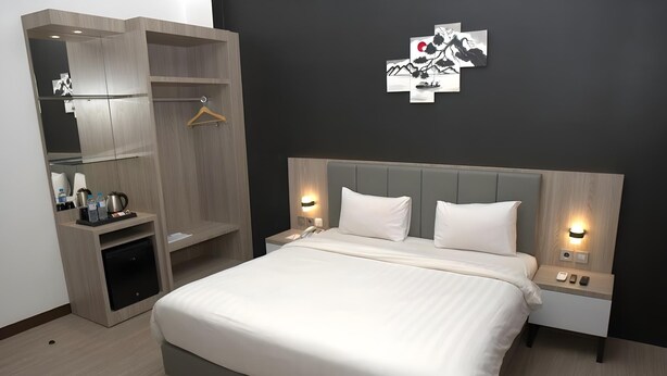 Una habitación de hotel moderna con una cama grande, mesitas de noche, un armario y una obra de arte colgada en la pared.