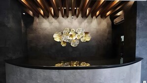 Un área de recepción con diseño moderno, que presenta una pieza decorativa central y un mostrador curvo y elegante.