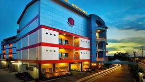 Un hotel de varios pisos con un diseño moderno, que cuenta con balcones y un logotipo destacado en la fachada.