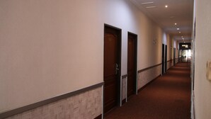 Un largo y estrecho pasillo de hotel con puertas de madera y una alfombra estampada.