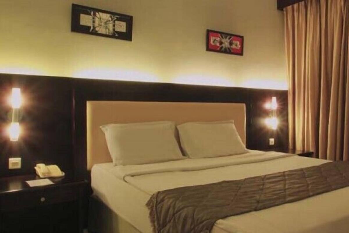 Ein Hotelzimmer mit einem Bett, einem Nachttisch mit Telefon und einer Wandlampe.