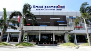Exterior del hotel y centro de convenciones Grand Permata, con un diseño moderno, que presenta una entrada destacada y palmeras al frente.
