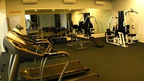 Ein Fitnessstudio mit Laufbändern, Kraftgeräten und Kurzhanteln.