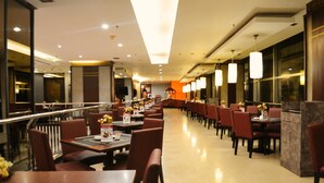 Ein geräumiges Restaurant mit mehreren Tischen und Stühlen, einem zentralen Gang und einem modernen Ambiente.