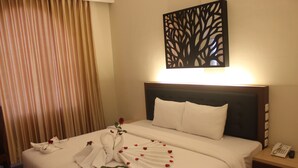 A hotel room with a neatly made bed, a wall-mounted phone, and a decorative tree pattern on the wall. - D'Salvatore Art & Boutique Hotel (Depok)