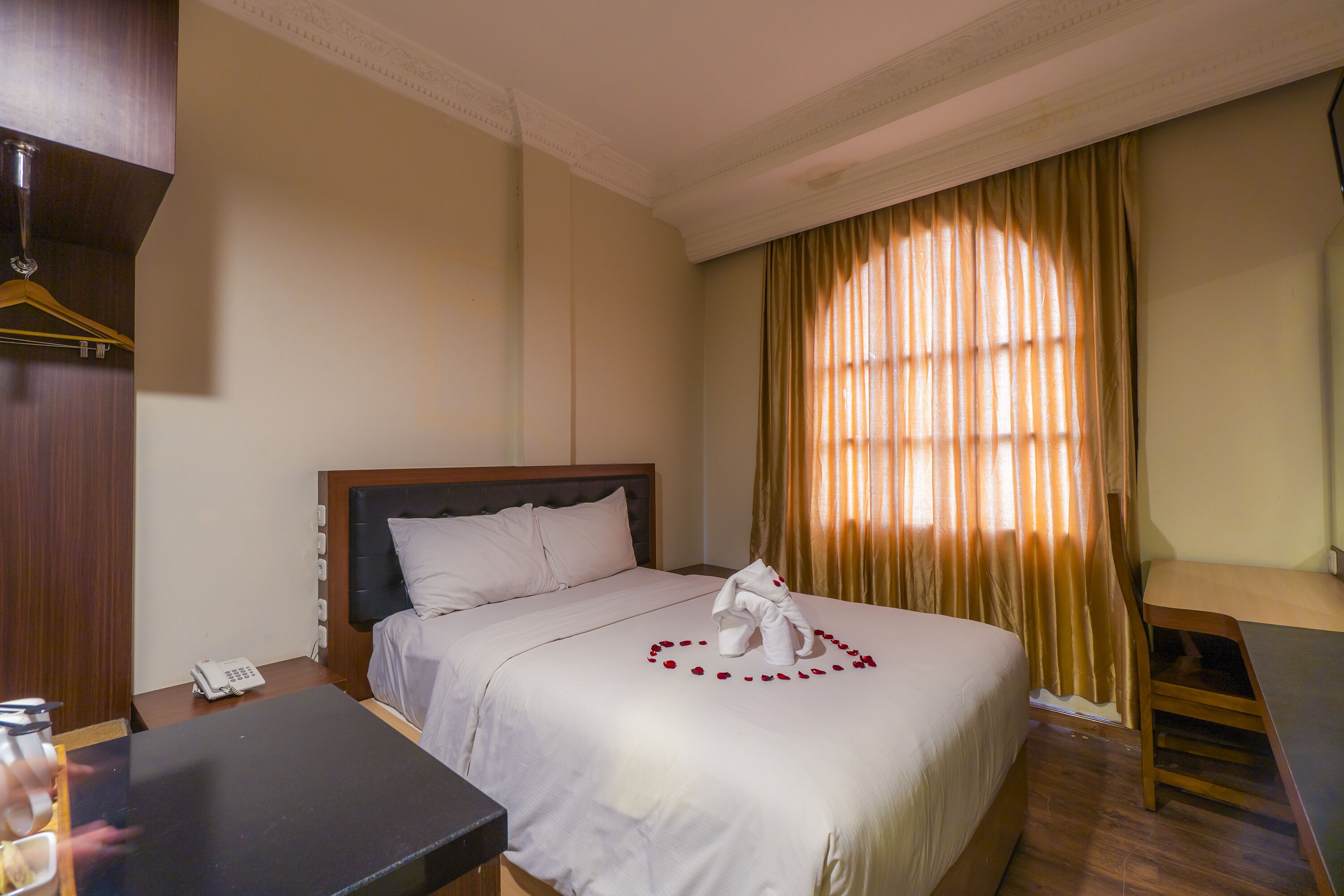 Une chambre d’hôtel avec un lit bien fait, une table de chevet avec un téléphone, un bureau et une chaise.