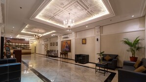 A spacious lobby with a high ceiling, marble flooring, and modern furniture including sofas and a reception desk. - D'Salvatore Art & Boutique Hotel (Depok)